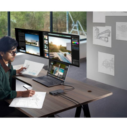 Person working at a desk with multiple monitors and laptop