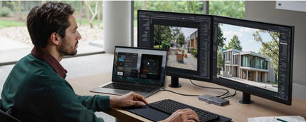 Man working at a desk with multiple monitors and a laptop.