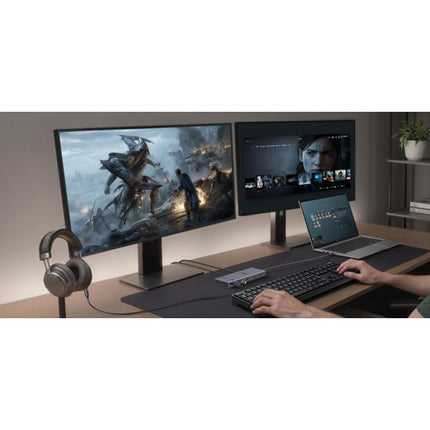 Gaming setup with two monitors, a laptop, keyboard, and headphones on a desk.