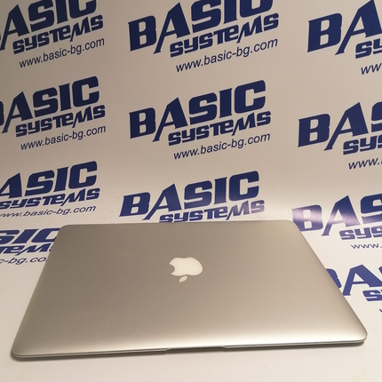 Поглед от горе на Лаптоп втора употреба Apple MacBook Air A1466 - CPU I7 5650U - 2,20Ghz, 8GB RAM, 128 GB SSD, HD Graphics 6000, (1440x900) в затворено положение на дисплея.На бял фон с лого basic systems www.basic-bg.com. Виждат логото на APPLE  ябълката на сребрист алуминиев корпус на дисплея на лаптопа втора ръка.